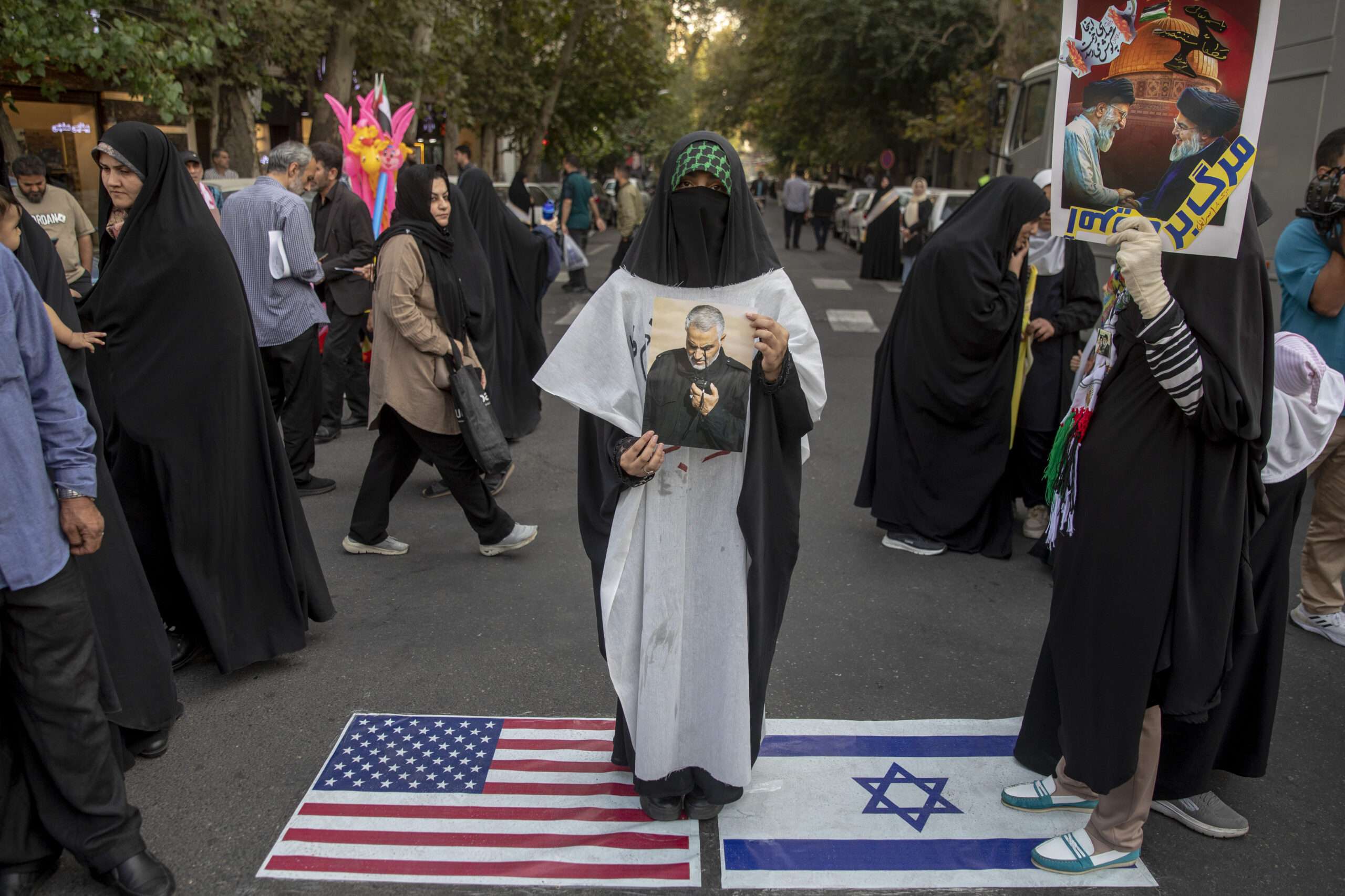 TEHRAN, IRAN - OCTOBER 8: Iranian demonstrators stand over immitation US and Israeli flags during an anti-Israel rally in Palestine Square on October 8, 2024 in Tehran, Iran. Renewed hostilities between long-time regional rivals Israel and Iran have been escalating since the Iran-backed militant group Hamas carried out attacks in Israel on October 7, 2023. Israel has since responded with continued strikes in Gaza and Lebanon, as well as targeted assassinations of Hamas and Hezbollah leaders. The killing of Iran-backed Hezbollah leader Hassan Nasrallah in an Israeli airstrike in Beirut last month prompted Iran to launch more than 180 missiles towards Israel. (Photo by Majid Saeedi/Getty Images)