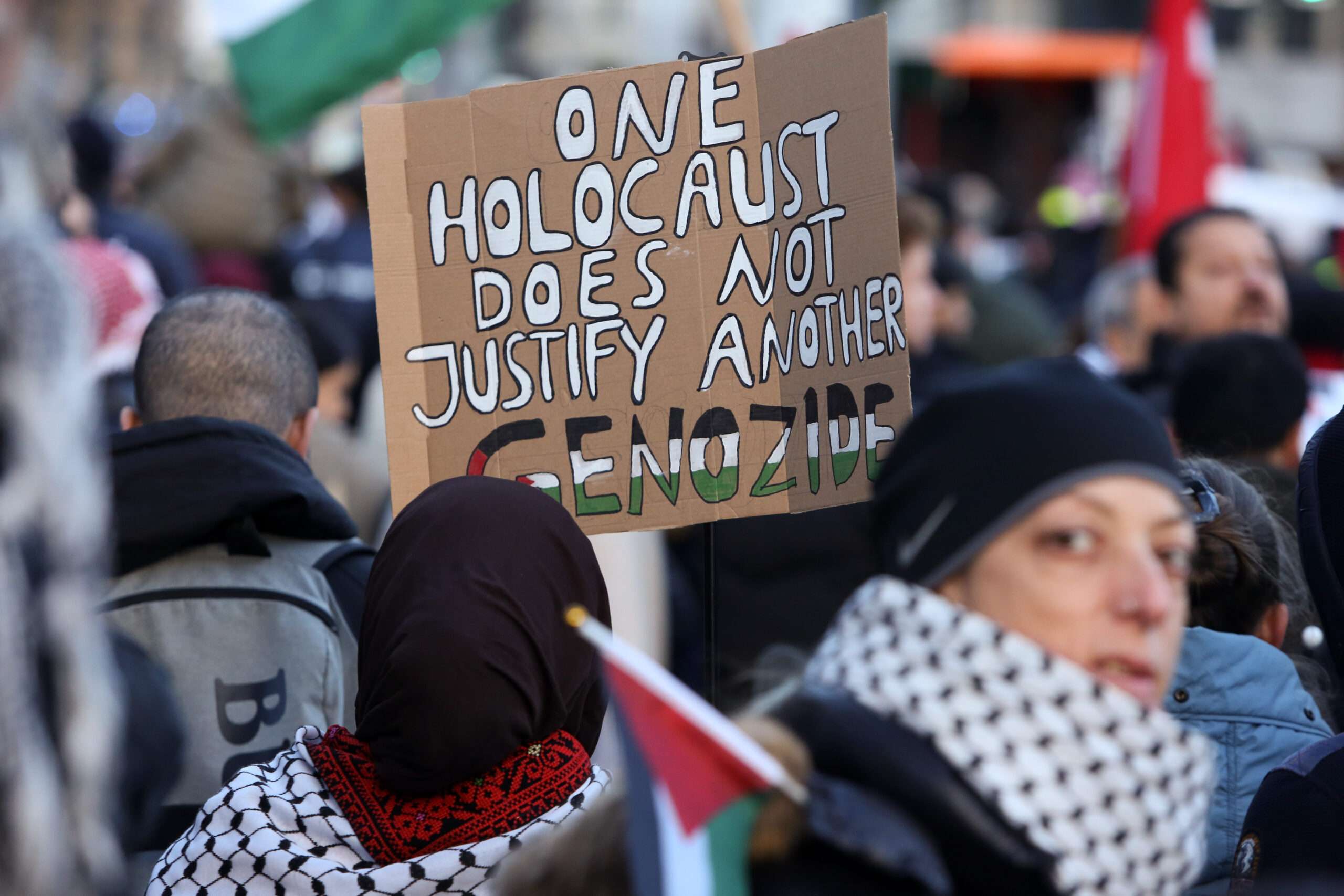 BERLIN, GERMANY - NOVEMBER 18: A protester holds a sign reading "One Holocaust Does Not Justify Another Genocide," with the last word written in German, as she attends a demonstration in support of Palestine amidst the ongoing war in Gaza, which the Israeli government says targets Hamas, the Palestinian Sunni Islamist political and military organization governing the Gaza Strip, on November 18, 2023 in Berlin, Germany. (Photo by Adam Berry/Getty Images)